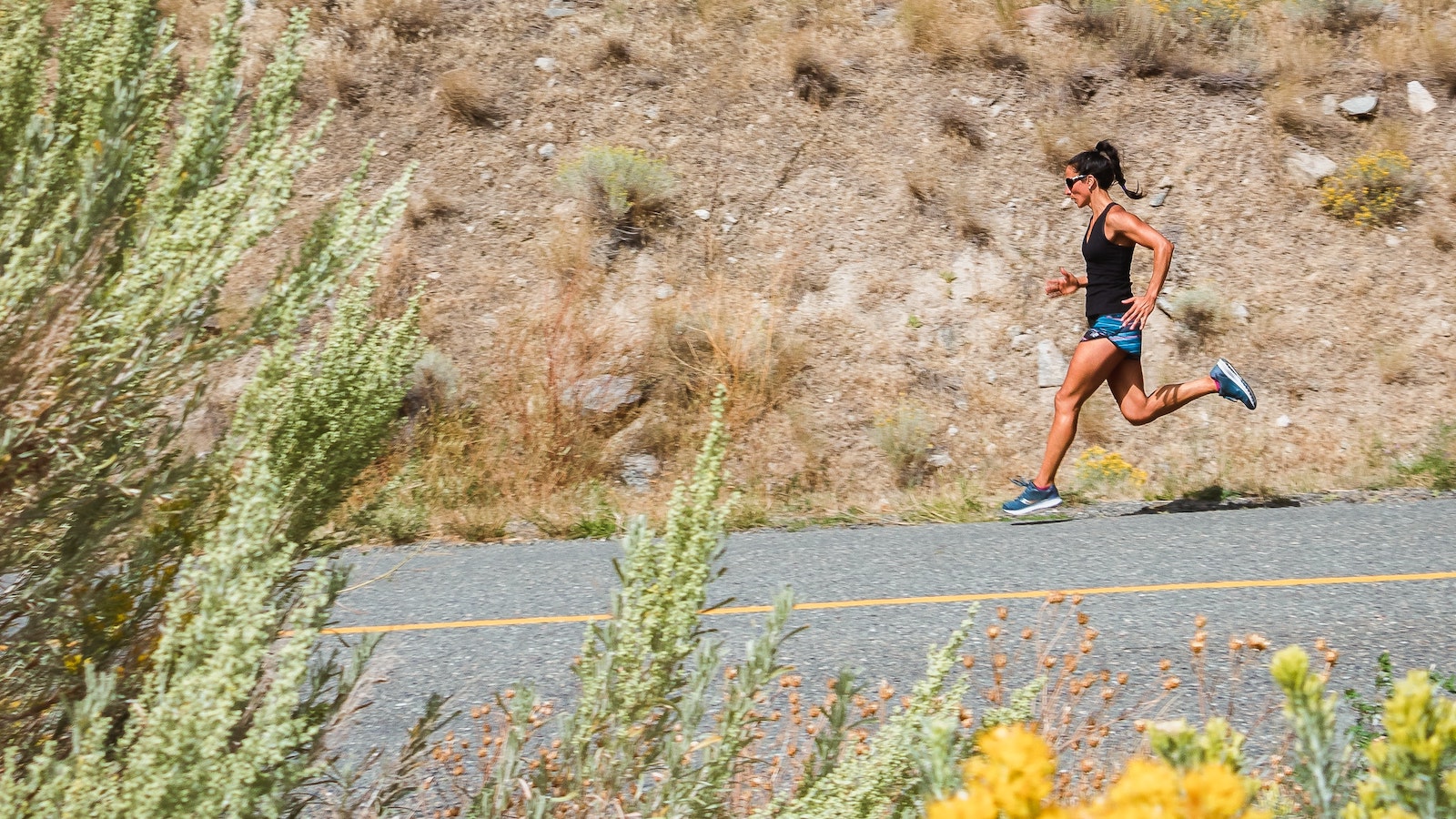 woman with sunglasses and black shirt running downhill