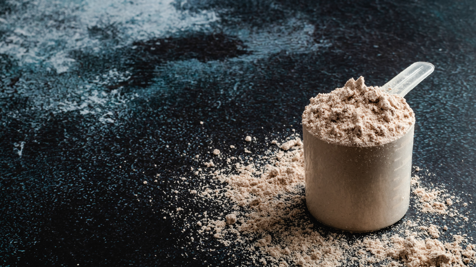 Chocolate protein powder in a clear scoop on a black background