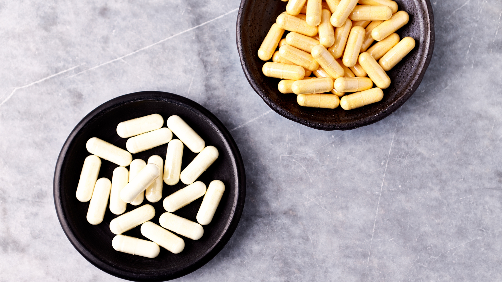 Alpha lipoic acid pills in a black dish on a gray background 