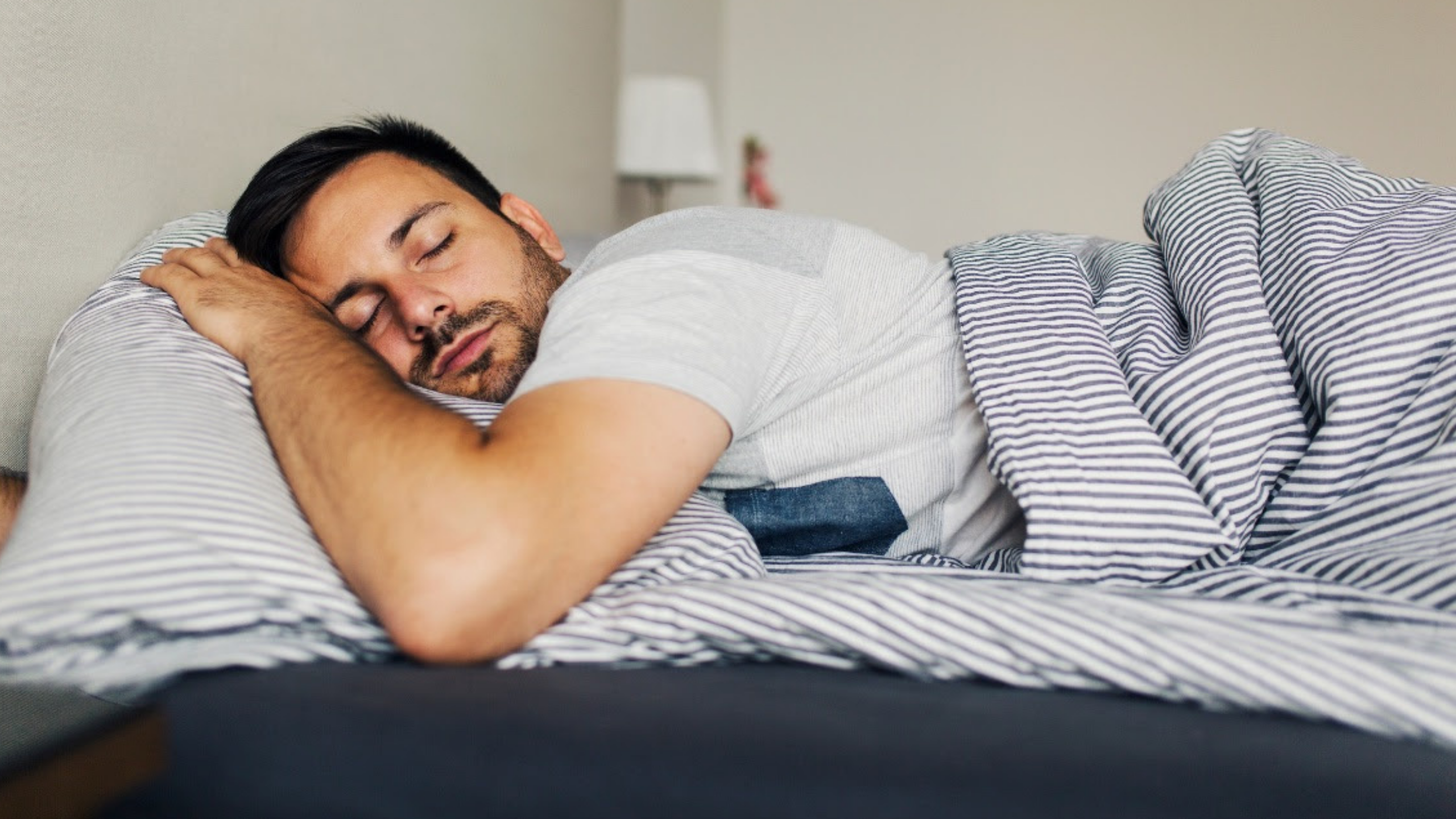 man sleeping on blue striped bedding 