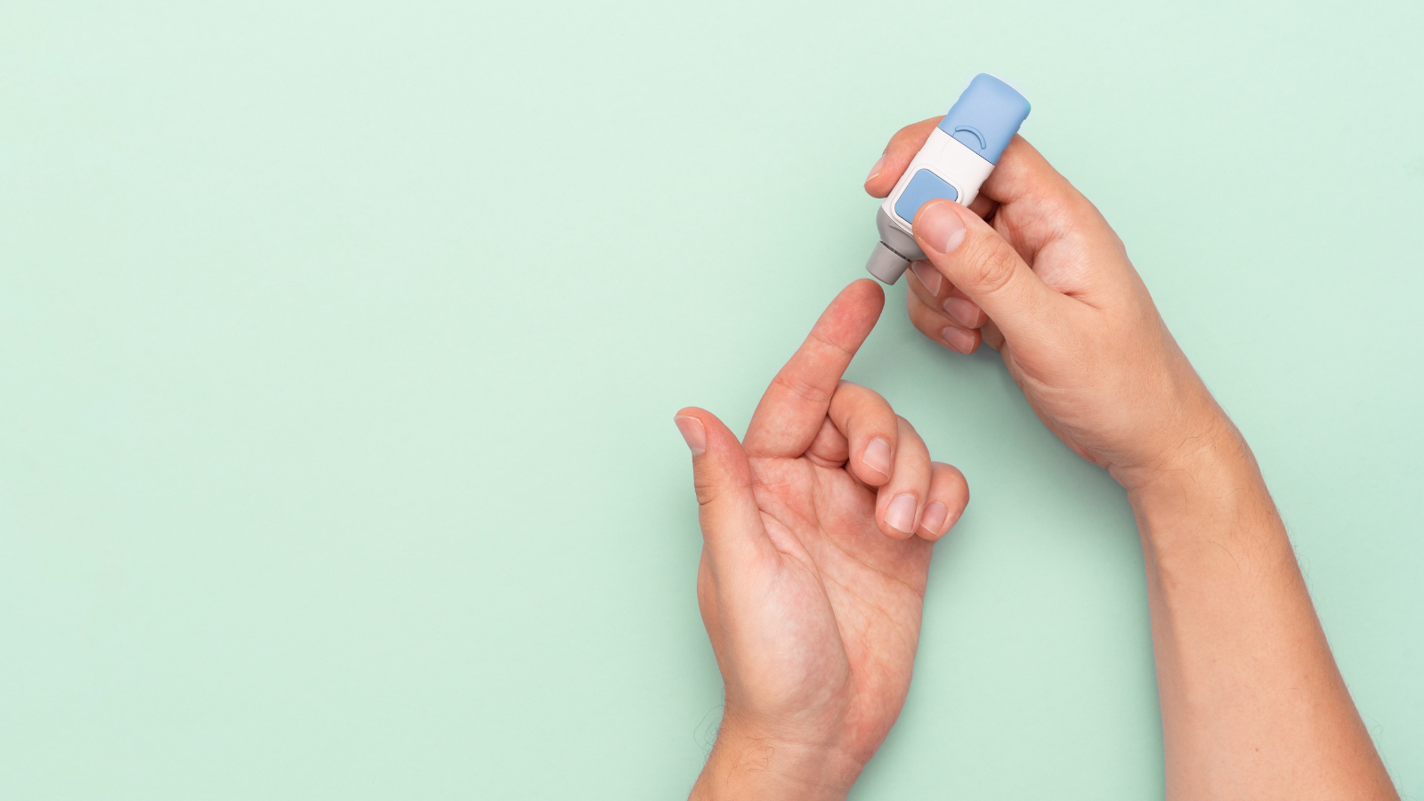 Person pricking finger with a lancet on a green background