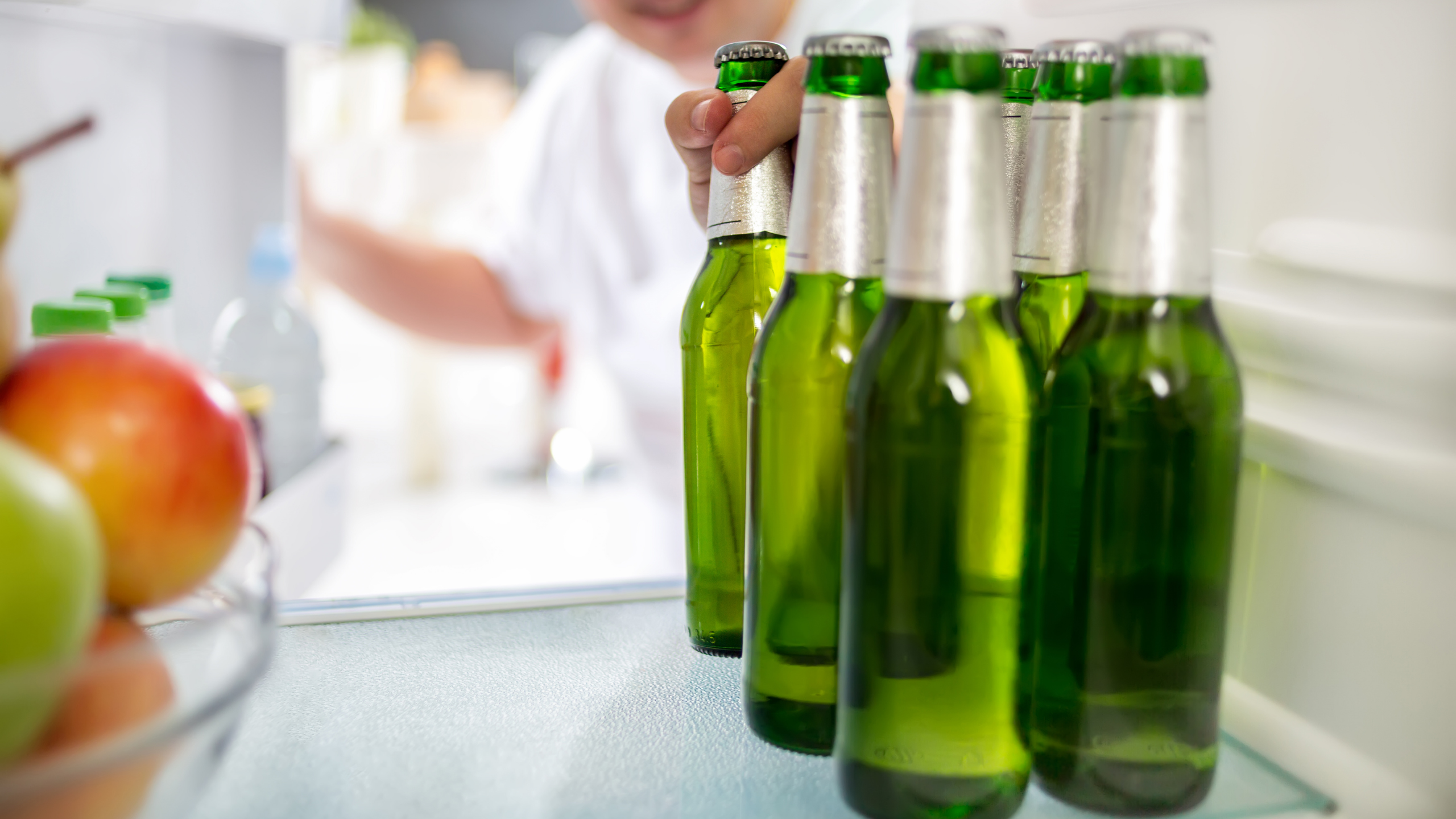 man grabbing beer bottle out of refrigerator