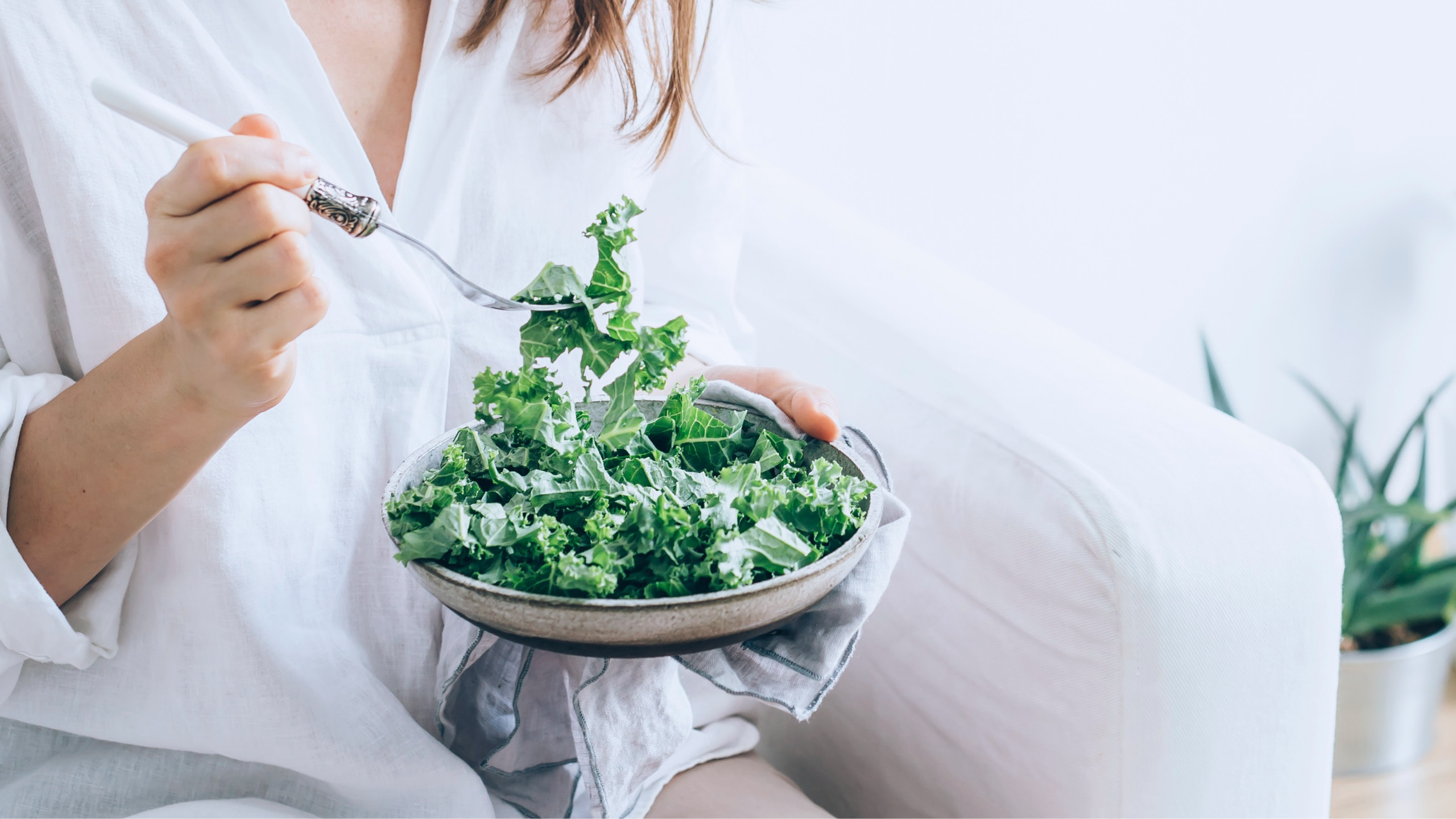 eating kale out of a salad bowl