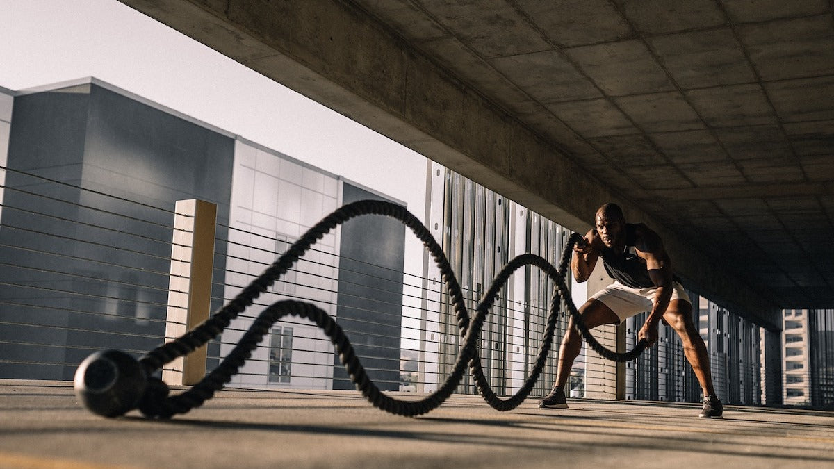 Black man doing a battle rope workout in a parking lot