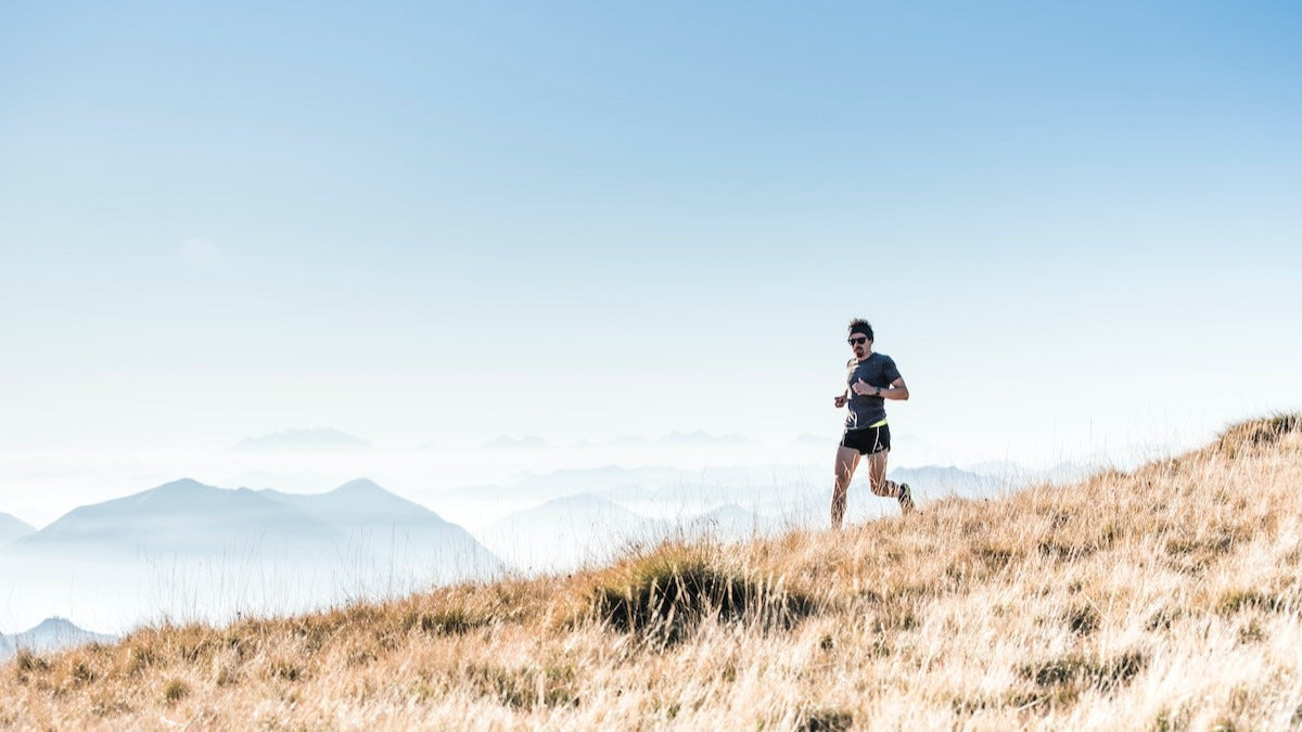 Male runner running downhill with mountains in the background