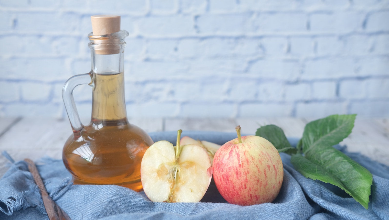 Apple cider vinegar in bottle with apples cut in half 
