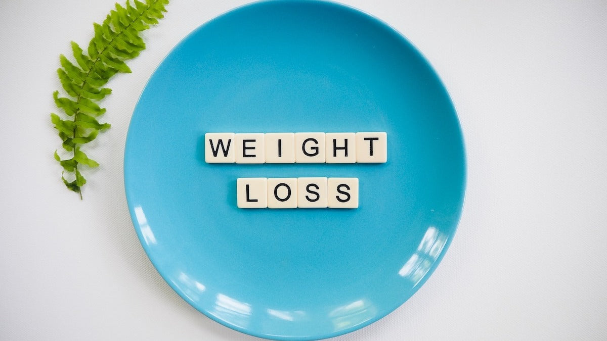 Weight loss spelled out in scrabble ties on a blue plate